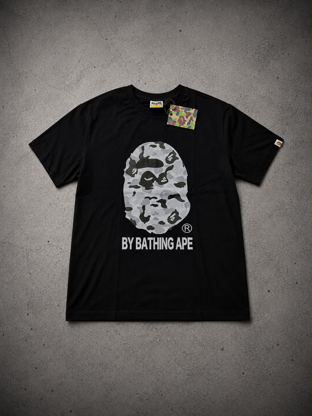 A BAPE black t-shirt, grayscale ape head logo, white text BY BATHING APE